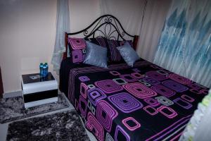 um quarto com uma cama com uma colcha rosa e roxa em JJ Homes - Podium Heights Apartment Nairobi em Nairobi