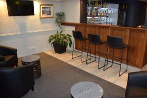un bar avec quatre tabourets et un comptoir avec des boissons dans l'établissement Best Western Coachman's Inn Motel, à Bathurst