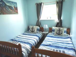 two twin beds in a room with a window at Chalet 26 Widemouth Bay in Bude