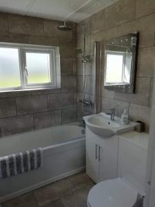La salle de bains est pourvue d'une baignoire, d'un lavabo et de toilettes. dans l'établissement Chalet 26 Widemouth Bay, à Bude