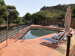 a swimming pool with two chairs and an umbrella at Jardines de La Santa in Totana