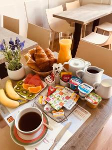 uma mesa de pequeno-almoço com alimentos de pequeno-almoço e café e sumo de laranja em Hôtel De La Cathédrale em Reims