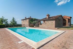 a large swimming pool in front of a house at Cottage Il Faldo in Paciano