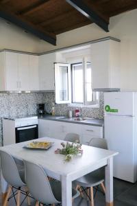 a white kitchen with a white table and chairs at Thealassa in Kalliópi