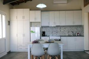 a kitchen with white cabinets and a table and chairs at Thealassa in Kalliópi