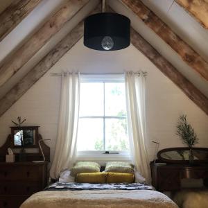 ein Schlafzimmer mit einem Bett und einem Fenster in der Unterkunft Cottage At 31 in Bundanoon