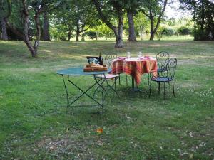 einen Tisch mit 2 Stühlen und einen Tisch mit einem Tischtuch in der Unterkunft La grange in Alluyes