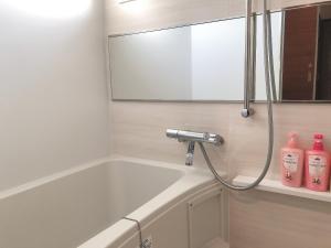 a bathroom with a bath tub and a mirror at TerraceRin YN23 in Tomigusuku