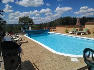 a swimming pool with chairs next to at Le Serpolet in Ozolles