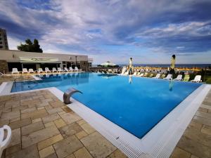 a large swimming pool with chairs and the ocean in the background at Hotel Olimpic in Jupiter