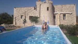 Eine Frau in einem Schwimmbad vor einem Schloss in der Unterkunft Villa Miliceddu in Tricase