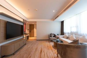 sala de estar con TV de pantalla plana grande en Zhong Tai Lai Hotel Shenzhen, en Shenzhen