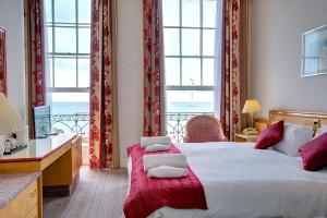 a hotel room with two beds and a desk and windows at Russell Hotel in Weymouth