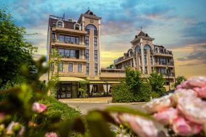 a building with two towers with pink flowers in the foreground at Boutique hotel Provence Бутик хотел Прованс in Petrich