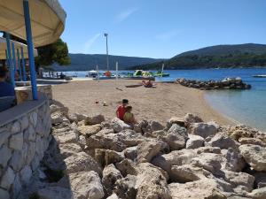 a man and a child sitting on a beach at Rooms Mario in Cres
