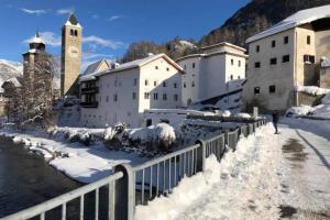 una persona che cammina nella neve accanto a un edificio di Loft 100m2, im Ökohaus in Susch a Susch