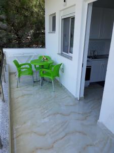 eine Terrasse mit einem grünen Tisch und Stühlen darauf in der Unterkunft Blue Coral apartament in Velipojë