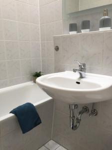 een witte badkamer met een wastafel en een bad bij Zwillingsperlen Leutzsch – Appartement Reiterhof in Leipzig