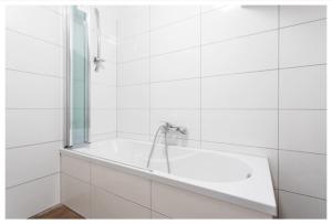 ein weißes Bad mit einer Badewanne und einem Spiegel in der Unterkunft N45 · Penthouse near Schoenbrunn. Amazing Terrasse! N45 in Wien