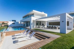 une maison blanche avec une piscine et des chaises blanches dans l'établissement The Villa / Ericeirahills, à Ericeira