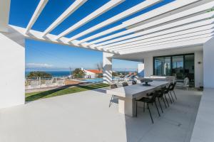 un patio con mesa, sillas y el océano en The Villa / Ericeirahills, en Ericeira