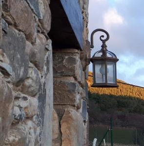 une lanterne suspendue sur le côté d'un mur en pierre dans l'établissement Albergue A'Noguera, à Castiello de Jaca
