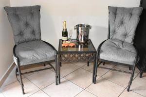 two chairs and a table with a bottle of champagne at Batter Boys Guest House in Pretoria
