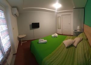 ein grünes Bett in einem kleinen Zimmer mit einem TV in der Unterkunft Ciuri Ciuri in Acireale