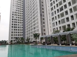 a swimming pool in front of two tall buildings at New Furnished 2BR Apartment at Serpong M-Town Residence By Travelio in Tangerang