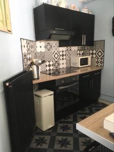 a kitchen with black cabinets and a counter top at Alice et Marie au Pays du Louvre in Lens