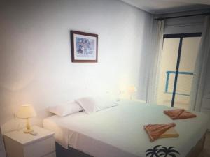 1 dormitorio con cama blanca y ventana en Playamarina 2 Cabo Roig, en Playas de Orihuela