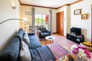 a living room with a blue couch and a television at Terraços de Benagil 23 (Casa Alvorada) in Benagil