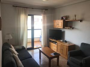 a living room with a couch and a tv and a table at Playamarina 2 Cabo Roig in Playas de Orihuela