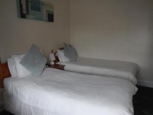 2 camas en una habitación con sábanas y almohadas blancas en Rob Roy Guest House, en Folkestone