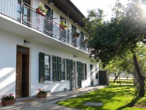 a white building with green shutters and a balcony at B&B Autin in Bruzolo
