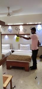 a man is making a bed in a room at Prithvi Hotels in Ahmedabad