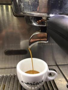 a cup of coffee is being poured into a coffee machine at RosAmar in Bari