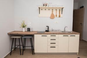 a kitchen with white cabinets and a sink and stools at Studio apartment Vukcevic 2 in Podgorica