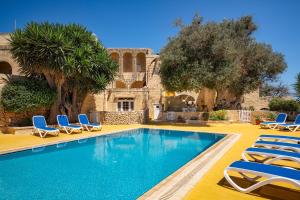 una piscina con sedie a sdraio e una casa di Razzett Ghasri a Għasri