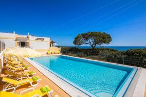 uma piscina com cadeiras e uma villa em Terraços de Benagil 23 (Casa Alvorada) em Benagil