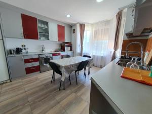 CisnădieにあるPensiunea Stanのテーブル付きのキッチン、赤いキャビネット付きのキッチン