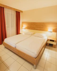 a bedroom with a large bed with a wooden headboard at Holiday Park Zelena Punta in Kukljica