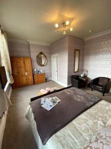 a bedroom with a bed and a couch and a mirror at The Fairmile in Lytham St Annes