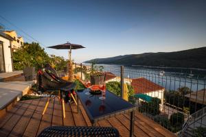 a table and chairs on a balcony with a view of the water at SUNSET APARTMENTS RABAC in Rabac