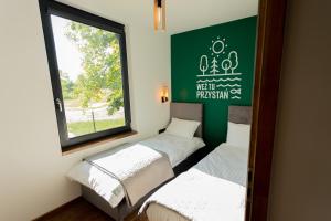 3 camas en una habitación con ventana en Weź tu Przystań, en Pomiechówek