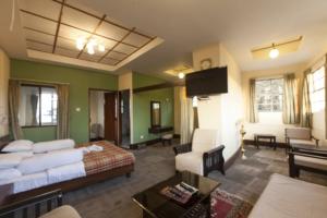 Habitación de hotel con cama y sala de estar. en Darjeeling Tourist Lodge en Darjeeling