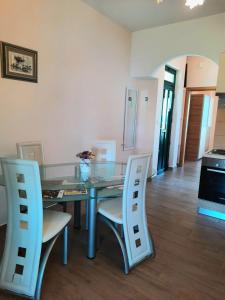 a dining room with a glass table and white chairs at Apartman Barbir in Sukošan