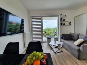 a living room with a couch and a table with fruit at Apartamenty Azure - 365PAM in Kołobrzeg