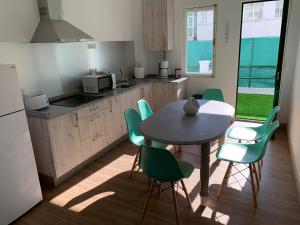 a kitchen with a table and green chairs in a kitchen at Apartamento Salomé in Padrón