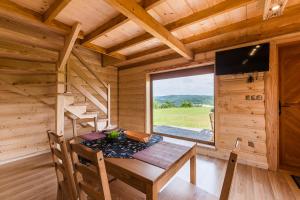 een eetkamer met een tafel en een raam in een blokhut bij Chaty Jak Dawniej in Wołkowyja